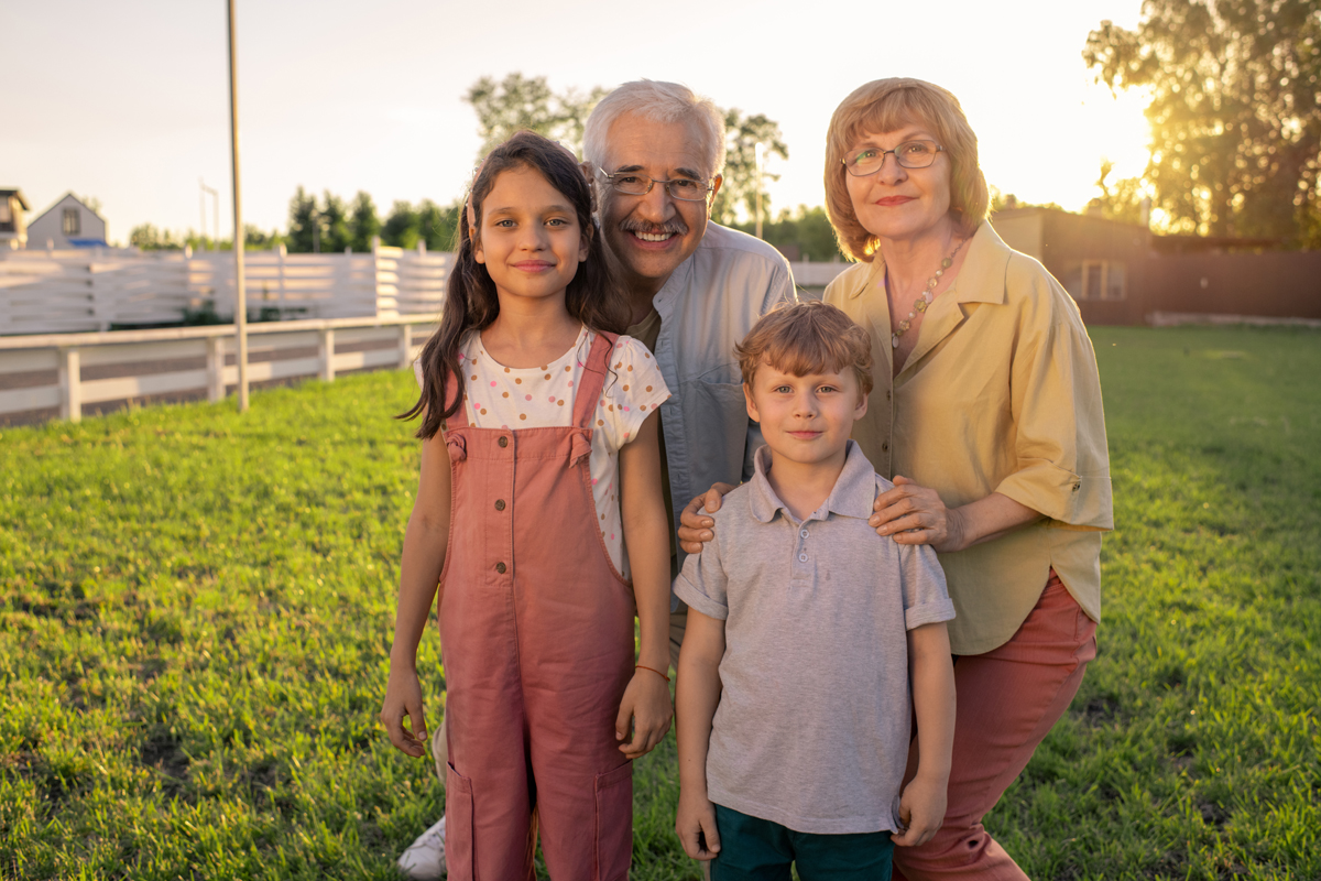 Happy grandparents and grandchildren standing in front of camera