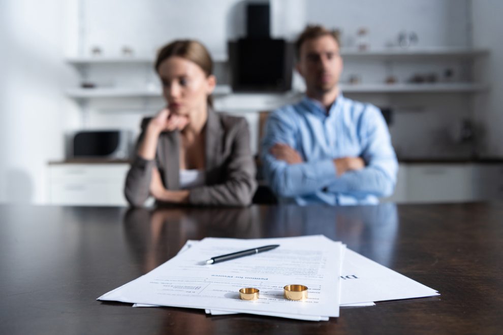 selective focus of couple sitting at table with divorce document